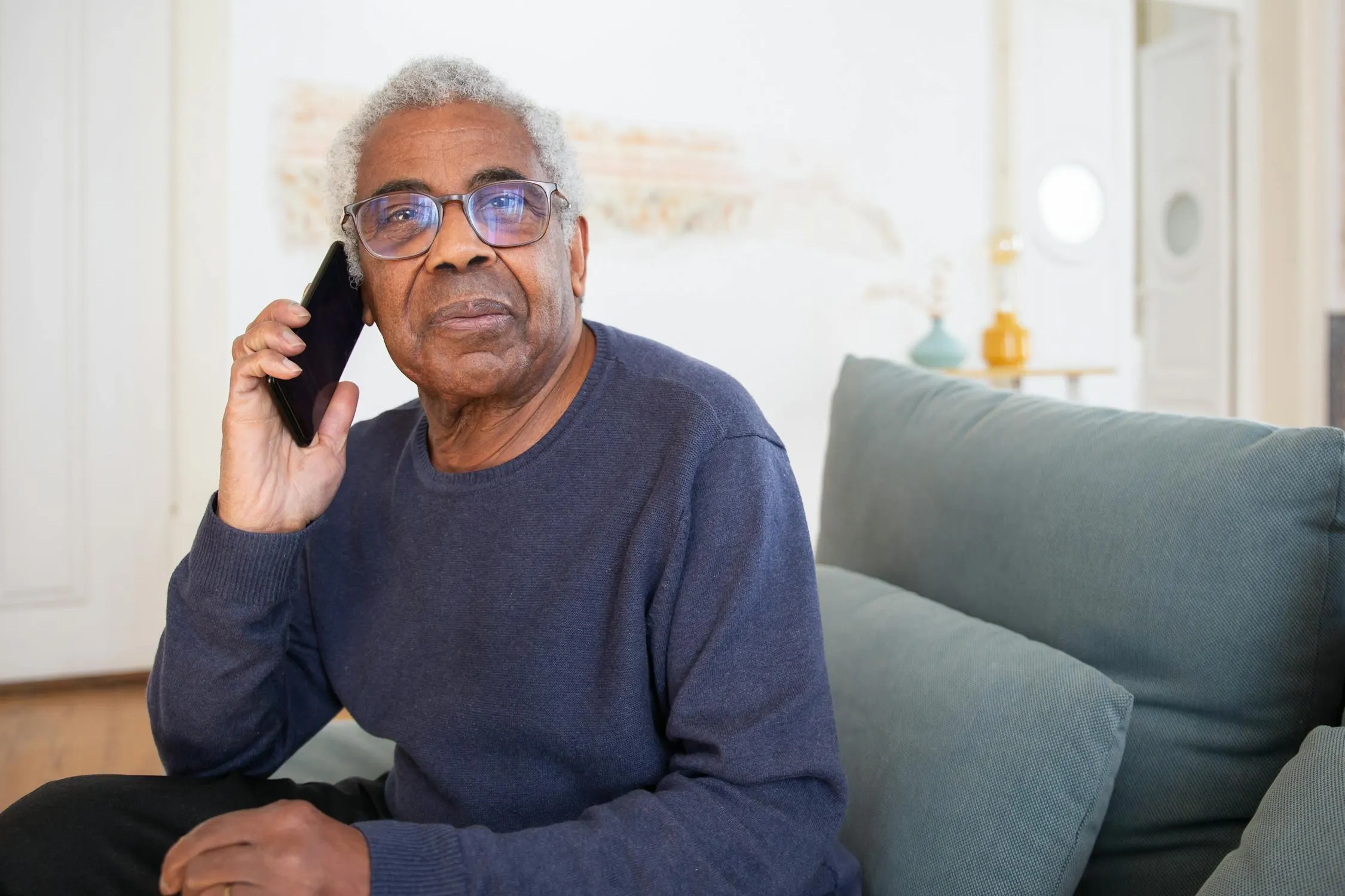 An older man holds a phone to his ear during a call
