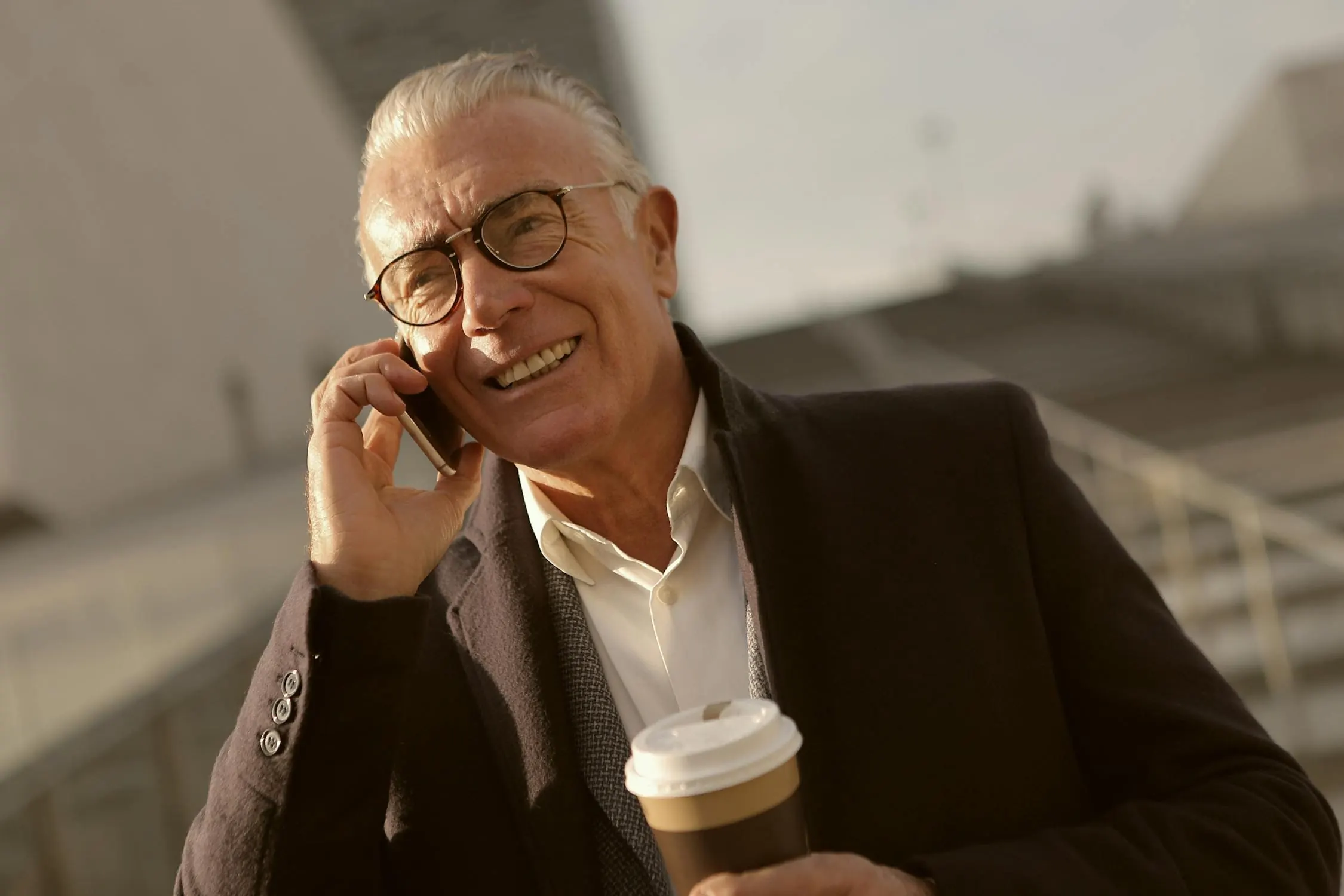 A senior man reads a large-text phone screen outdoors in bright light